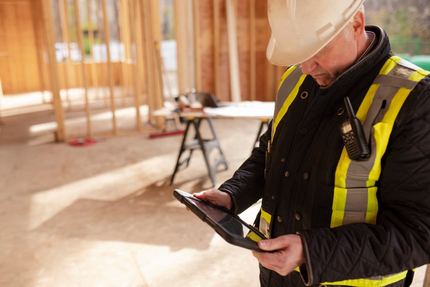 Foreman using digital tablet in house under construction Bygningsarbeider jobber digitalt med nettbrett
